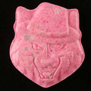 Big Cat With Hat MDMA pill in bright pink color placed against a black surface. Big Cat With Hat MDMA For Sale