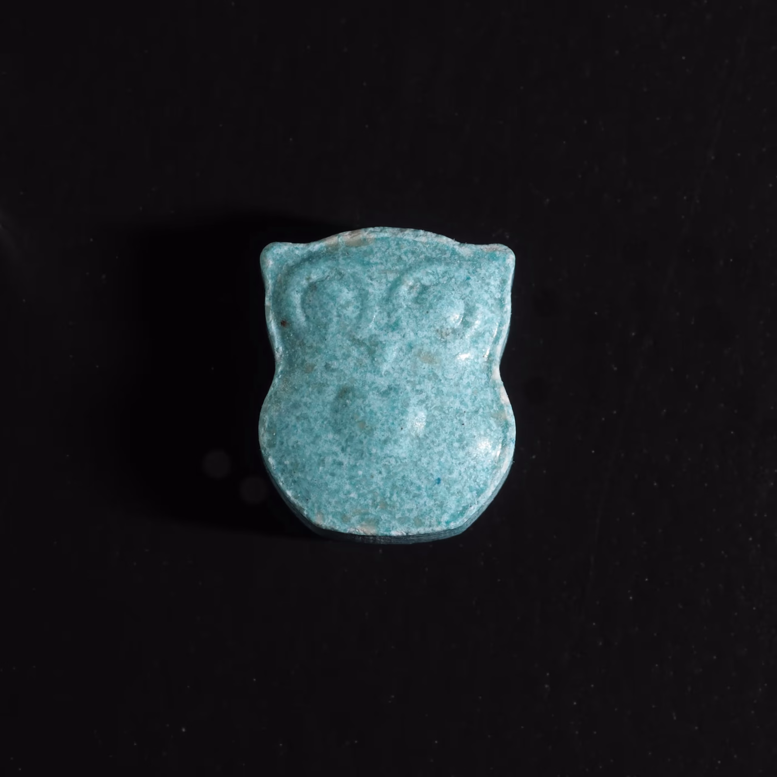 Close-up of Owl MDMA tablets placed on a black surface. Owl MDMA For Sale